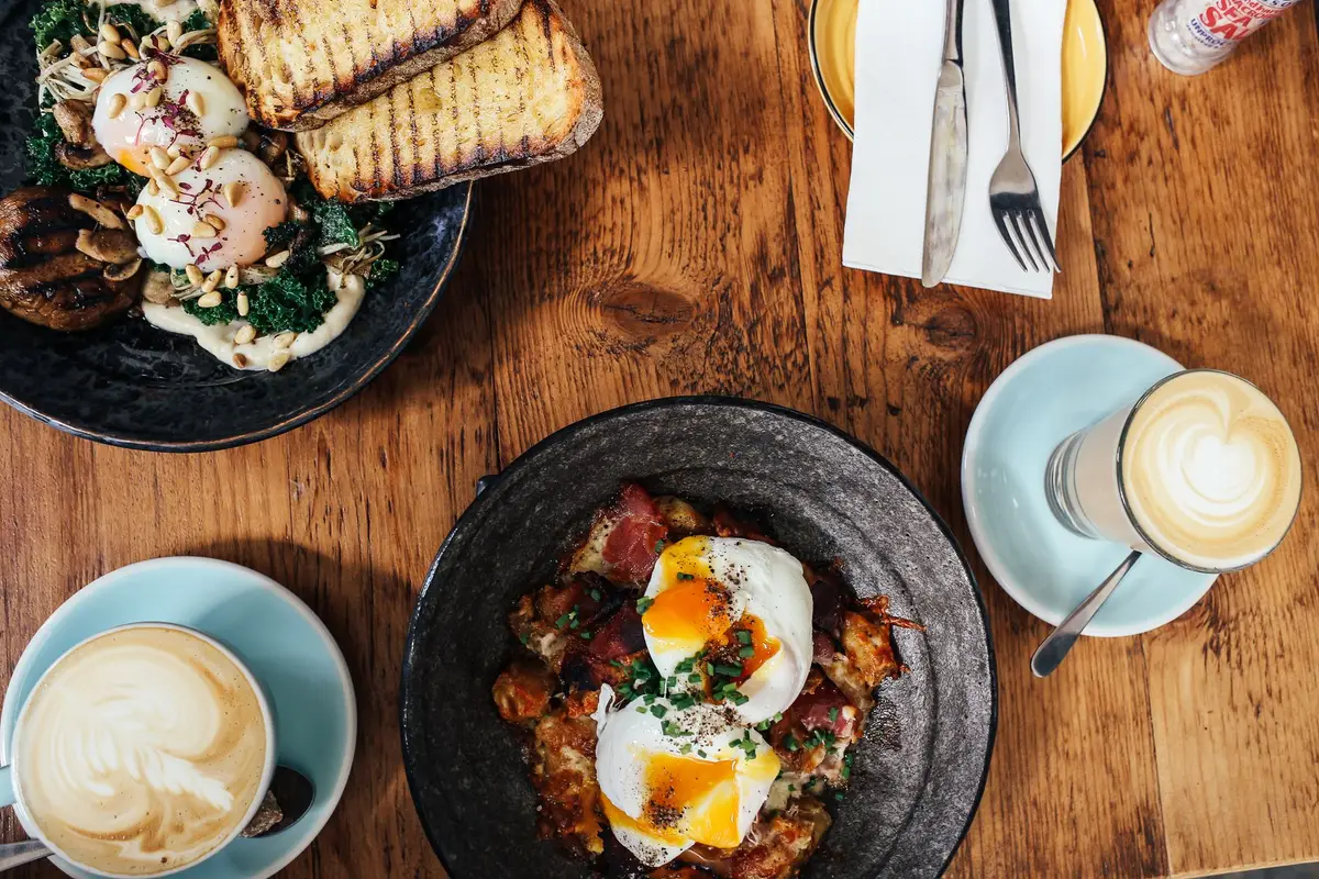 Brunch table with poached eggs, toast and lattes seen from above